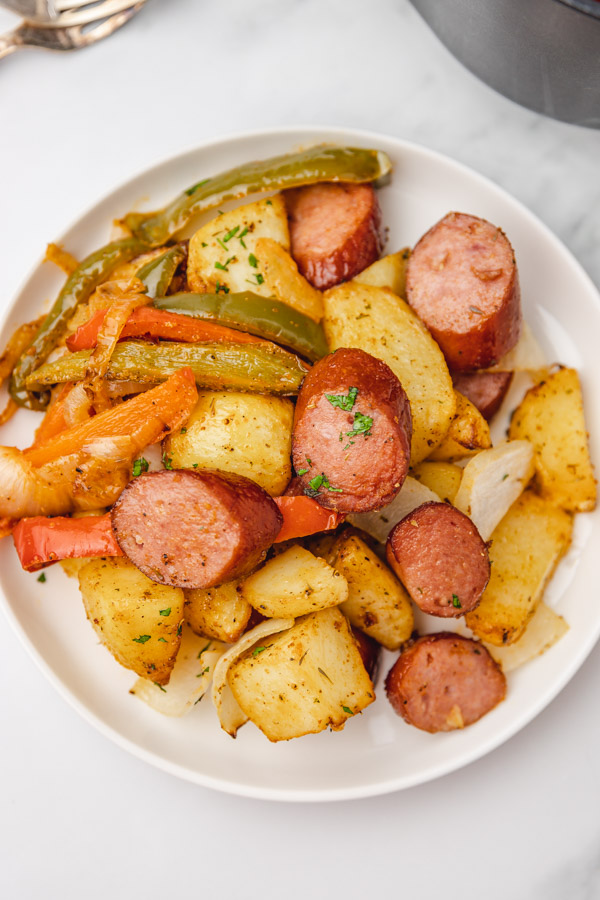 a plate of diced roasted potatoes with sliced keilbasa sausages and sauteed peppers.