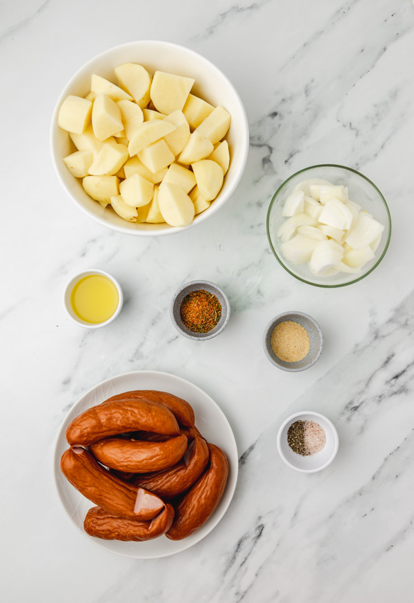 ingredients to cook potato and sausages on a counter.