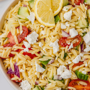 a bowl of lemon orzo salad with feta cheese crumbled on the top.
