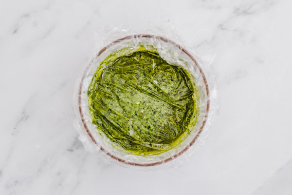a bowl of pesto corvered with clingfilm.