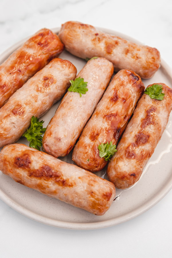 seven cooked sausages on a beige side plate.