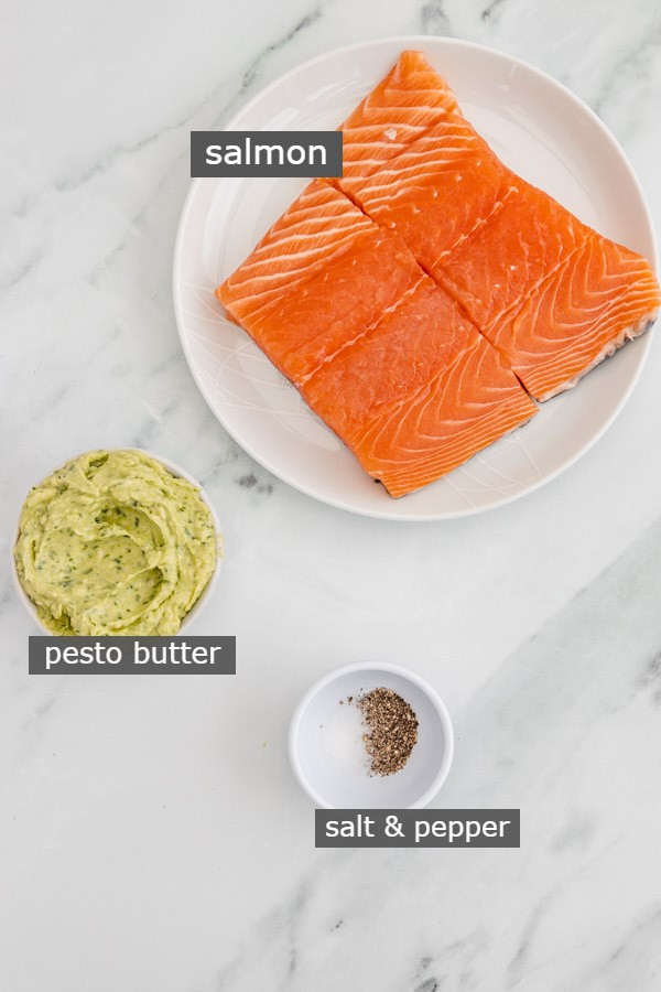 the ingredients needed to make pesto salmon set against a marble surface.