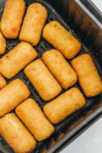 freshly cooked potato croquettes in the air fryer basket.