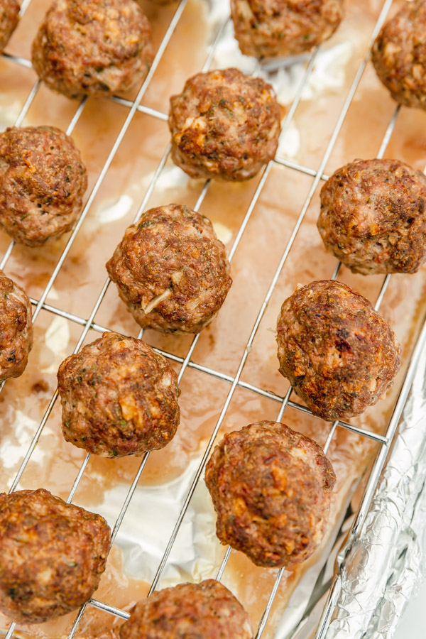 baked meatballs on wire rack placed on a baking sheet.