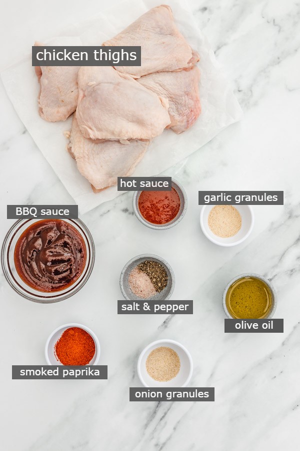 the ingredients to make bbq chicken thighs on a marble surface.