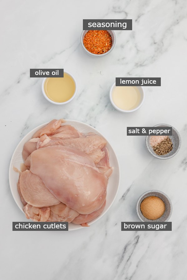 the ingredients needed to make broiled chicken placed on a white marble surface.