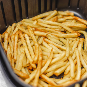 crispy and golden brown frech fries in an air fryer basket.