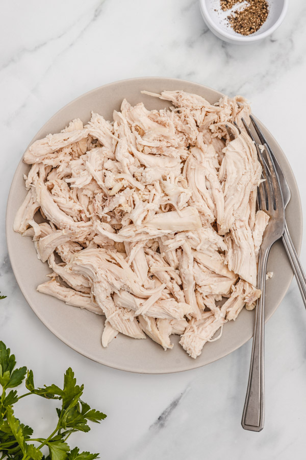 shredded chicken breast on a plate with two forks.