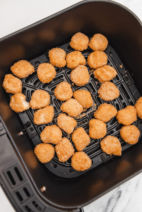 chicken nuggets arranged in air fryer basket.