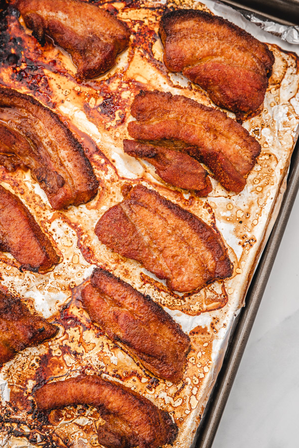 baked pork belly slices on a baking tray.