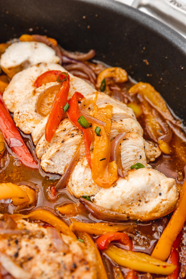 sliced chicken breast resting in the pan  juice of peppers and onions.