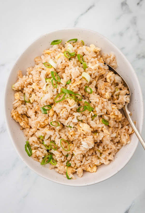 a bowl of egg fried rice garnished with sliced scallions.
