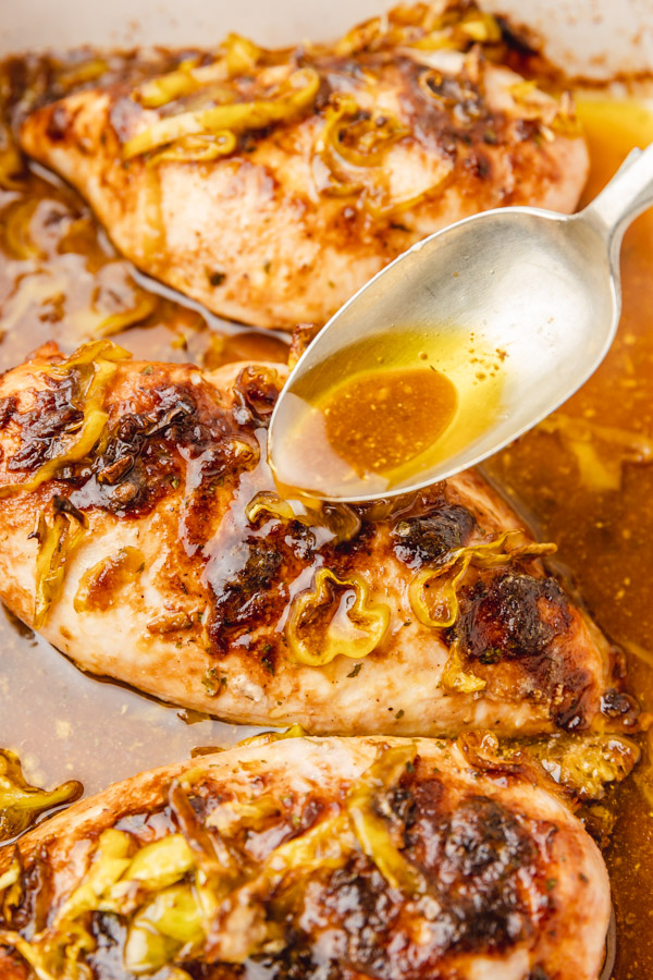  spoon with pan juice over baked chicken breast.