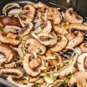 cooked mushrooms and onions in air fryer basket.