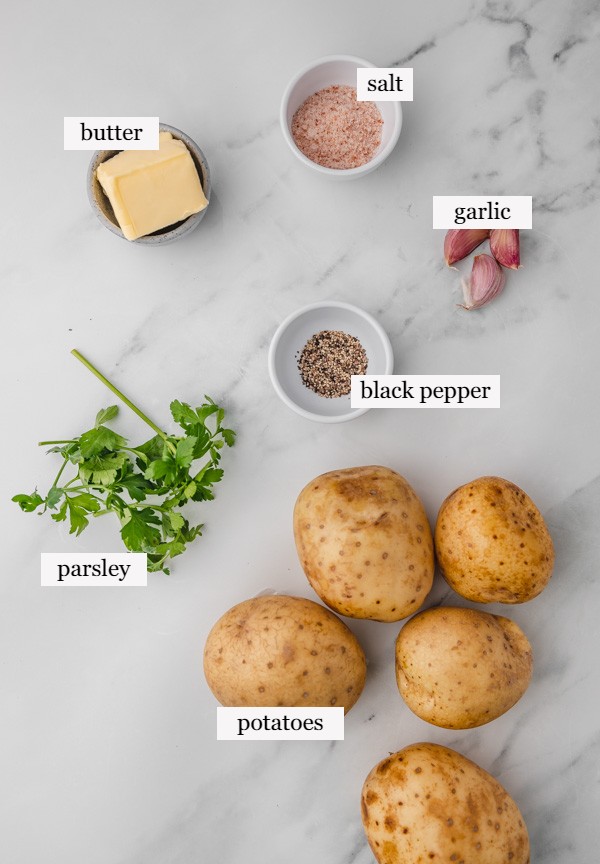 the ingredients needed to make boiled potatoes with butter, garlic and parsley.
