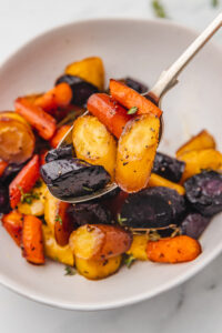 roasted rainbow carrots on a serving spoon.
