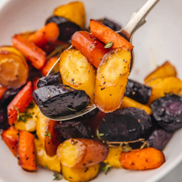 roasted rainbow carrots on a serving spoon.