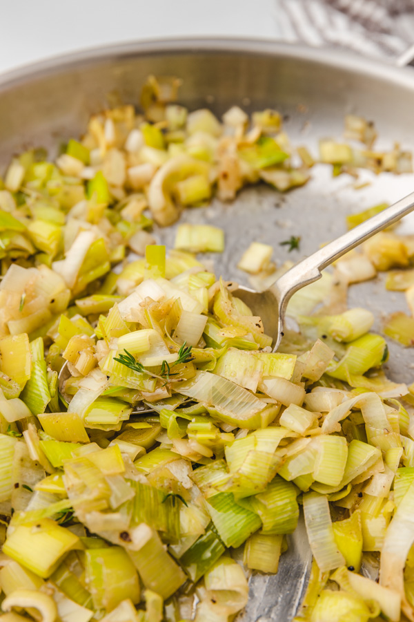 sauteed leeks on a spoon in a skillet.