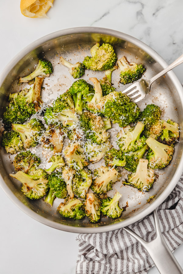 sauteed broccoli garnished with grated parmesan cheese in a skillet.