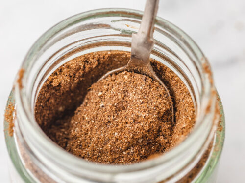 lebanese 7 spice in a glass jar with spoon.