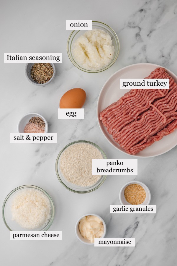 ingredients to make turkey meatballs placed on a white marble surface.