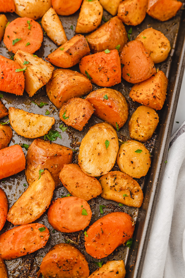 roasted vegetables carrots parsnip and sweet potatoes in a rimmed baking sheet.