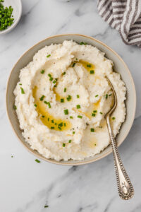 a bowl of cauliflower mash topped with melted butter and chives