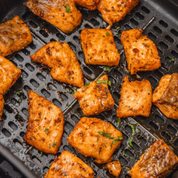 cooked salmon bites in an air fryer basket.
