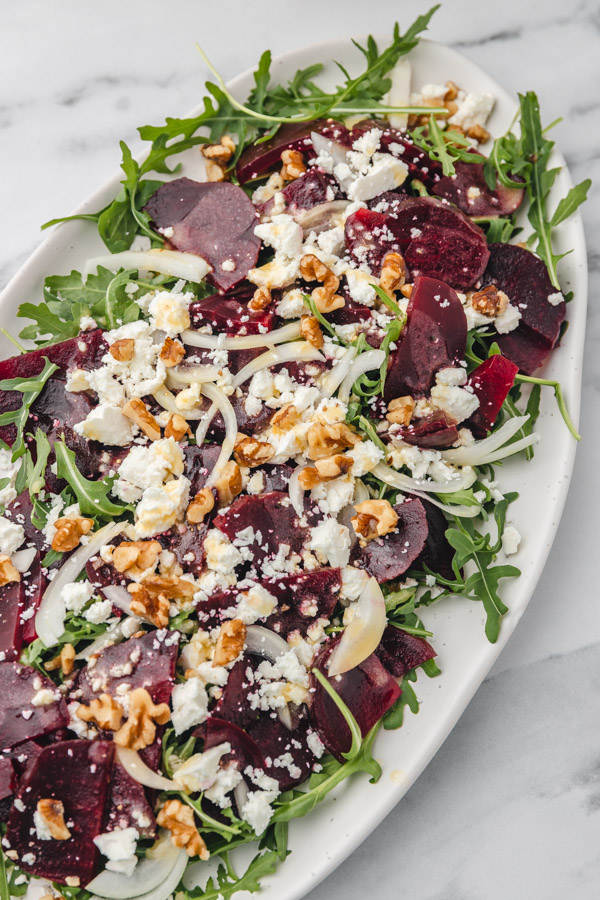 a plate of beetroot salad with deta cheese and chopped walnuts.