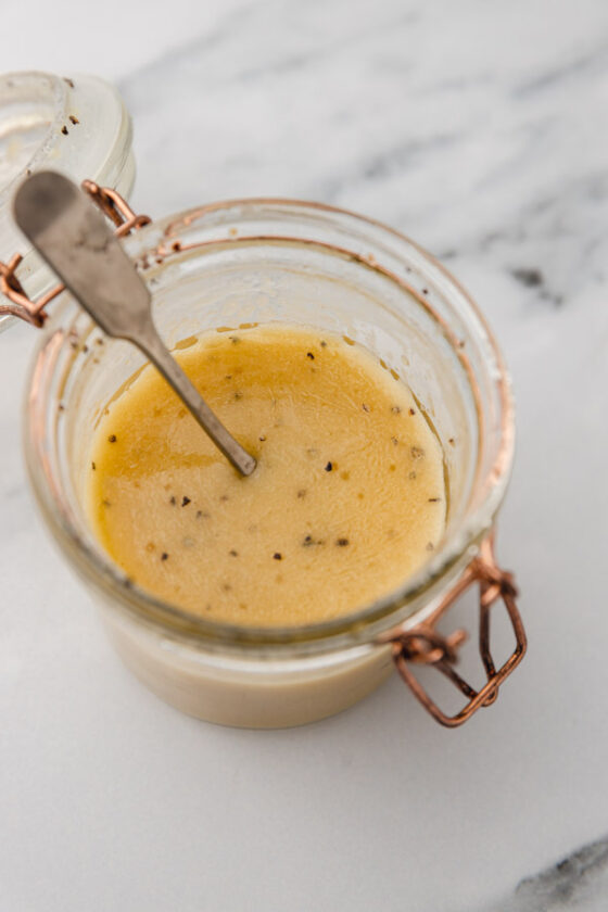 honey mustard dressing in a mason jar with a spoon.