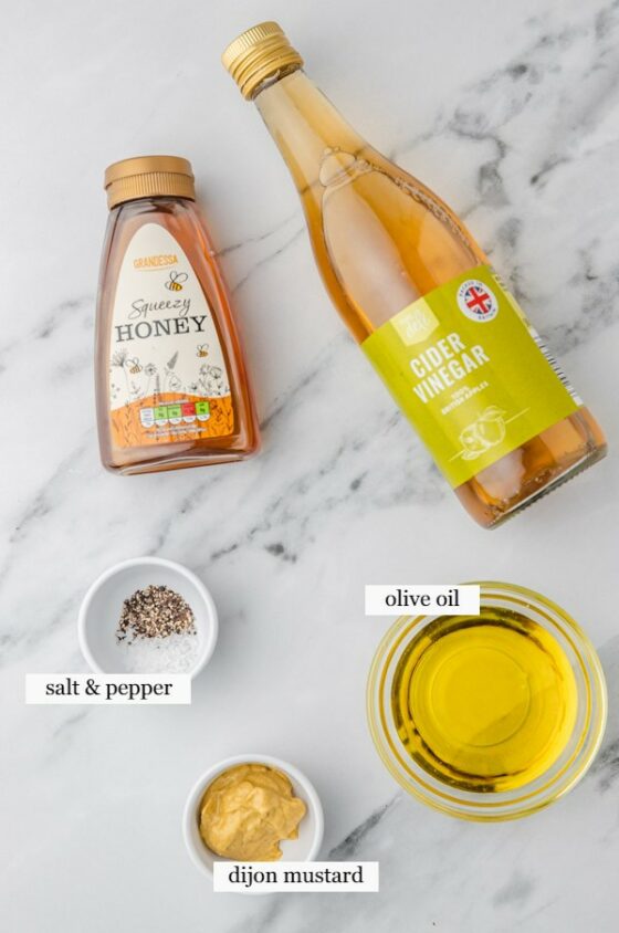 ingredients to make honey mustard sauce placed on a marble surface.