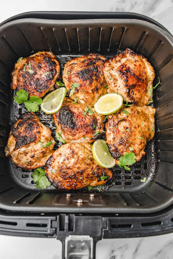 cooked cilantro lime chicken thighs in an air fryer basket.