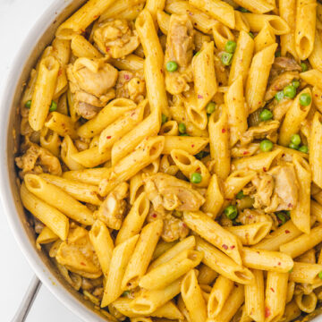 curry pasta with chicken and peas in a skillet.