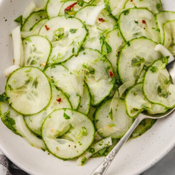 a bowl of cucumber salad with a spoon.
