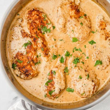 creamy chicken in a skillet placed beside a white napkin.