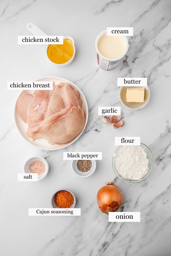 ingredients needed to make cajun chicken on a marble surface.