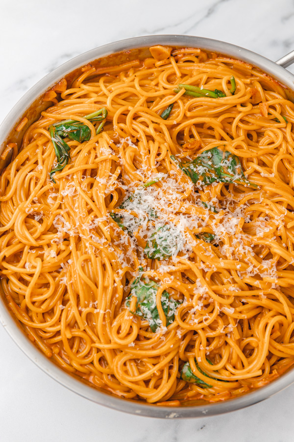 creamy Gochujang pasta in a skillet garnished with grated parmesan cheese.