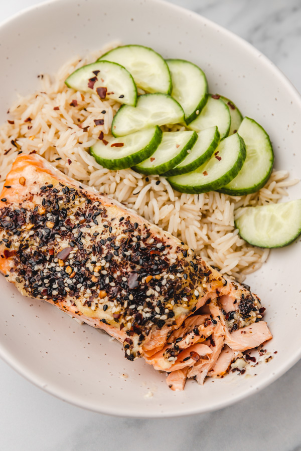 a bowl of salmon, rice and cucumber.