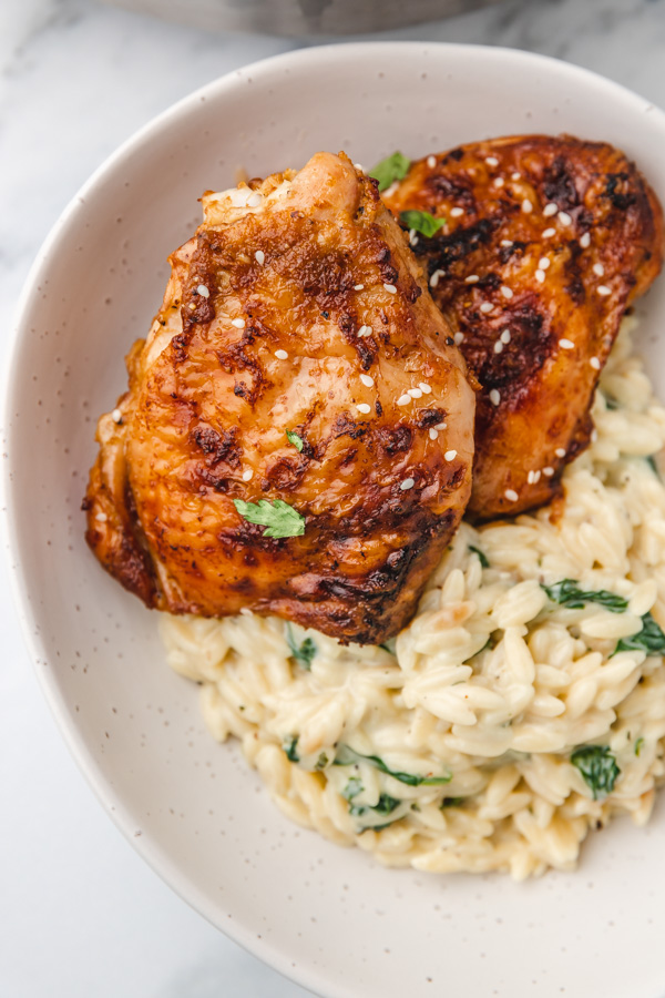 a bowl of creamy orzo and chicken thighs,