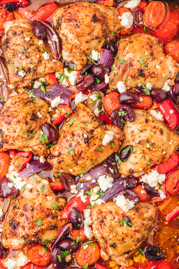a close up of greek chicken on a sheet pan.