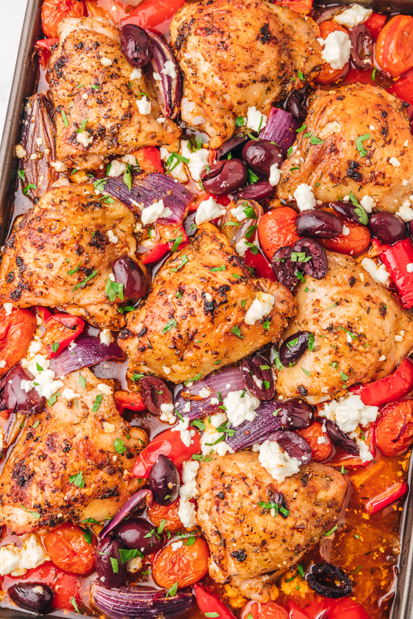 chicken thighs in a baking dish with vegetables and feta cheese.