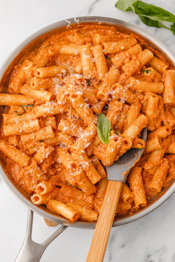 creamy tomato ricotta pasta in a skillet with a spatula.