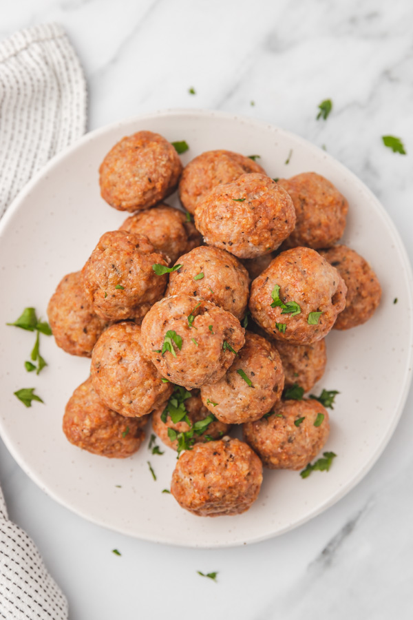 pork meatballs on a plate garnished with chopped parsley.