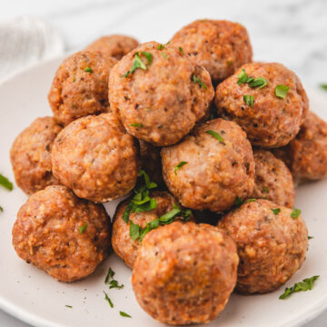 baked pork meatballs stacked on top of one another on a plate.