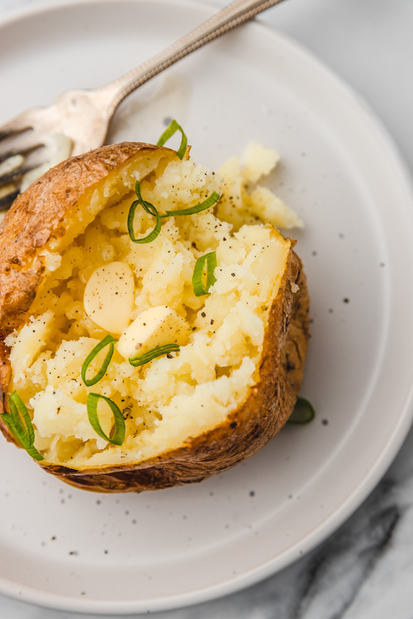 baked potatoes, fluffed and seasoned with black pepper, butter and garned with chopped spring onion.