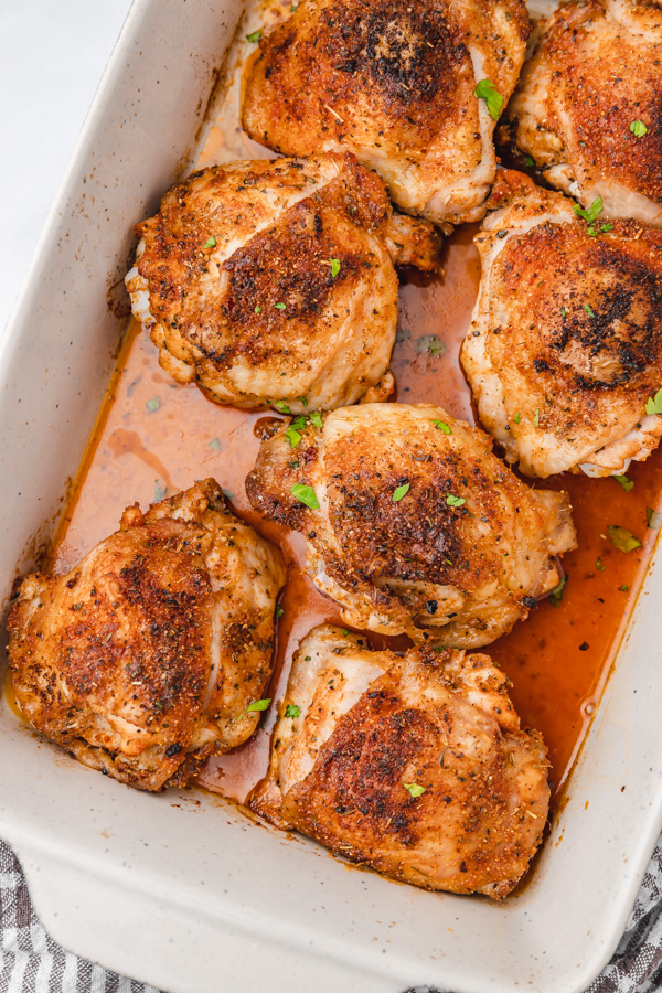 seven baked cripsy chicken thighs in a baking dish.
