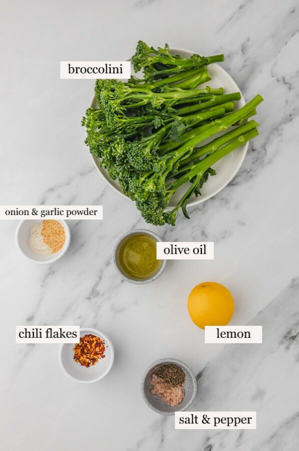 ingredients to cook broccolini on a white marble surface.