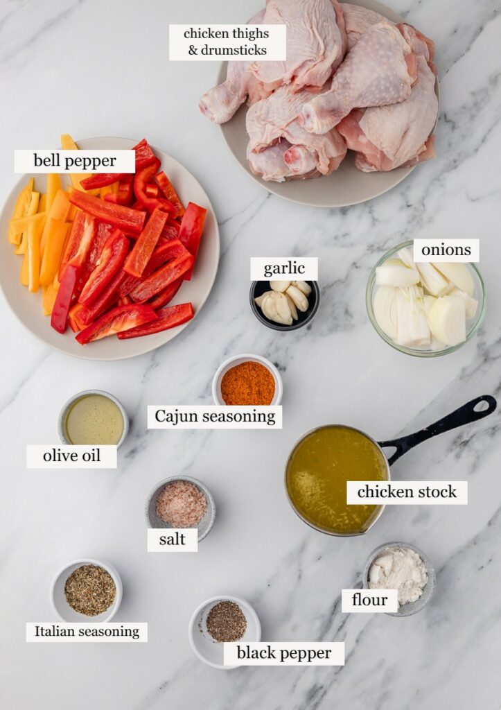 ingredients for chicken and peppers on a white marble surface.