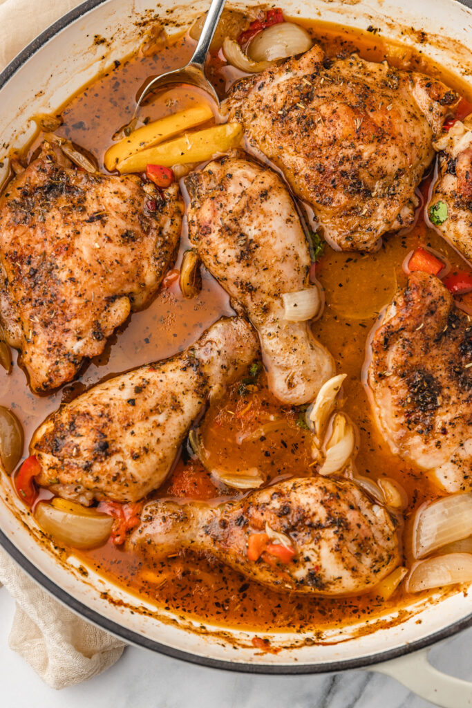 a spoon pushing pepper in a dutch oven of chicken.
