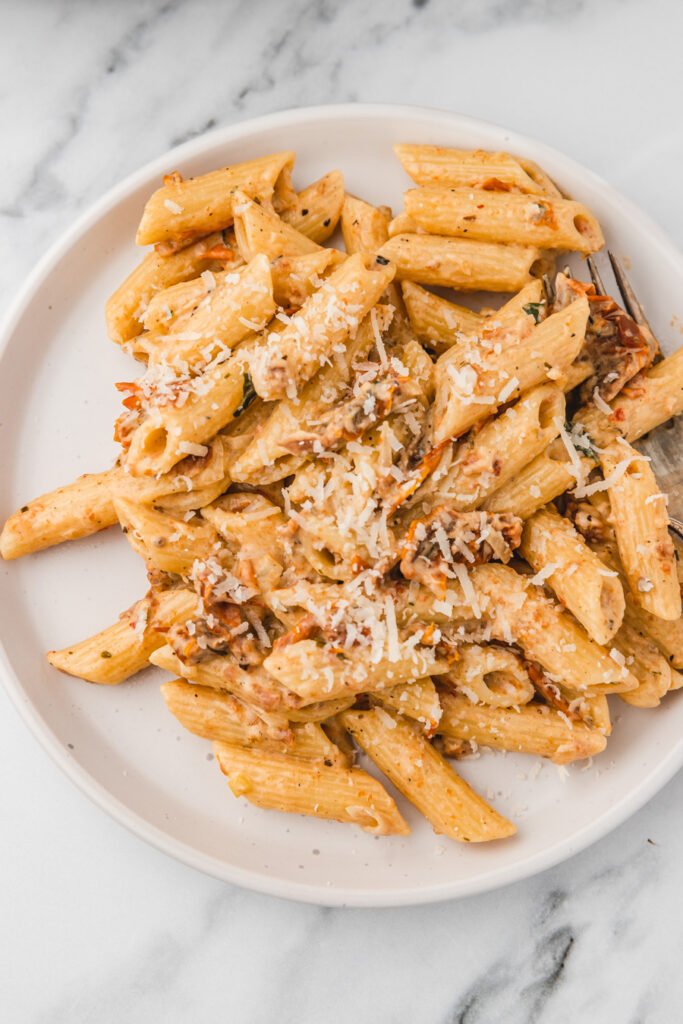 a plate of creamy sundried tomatoes garnished with grated parmesan cheese.